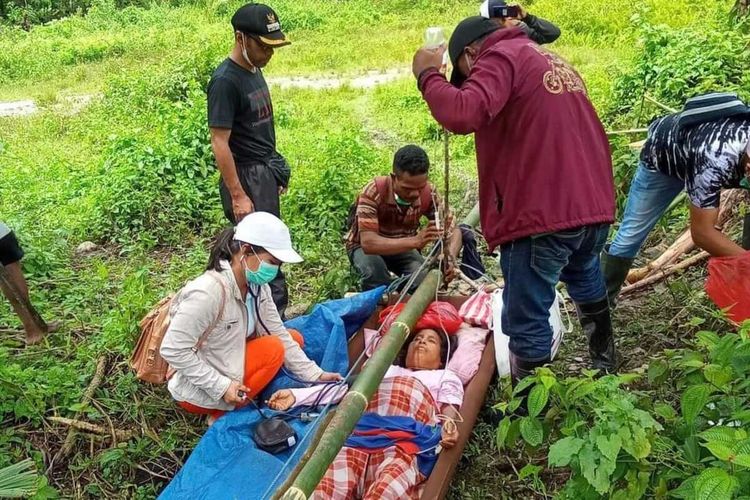 Tim medis dari Puskesmas Elpaputih memberikan pertolongan pertama bagi Yuliana Lasattira (40) di tengah hutan. Yuiliana ditandu keluarganya dari desa Huku Kecil menuju Puskesmas Elpaputih yang jaraknya 37 km pada Jumat (20/8/2021).