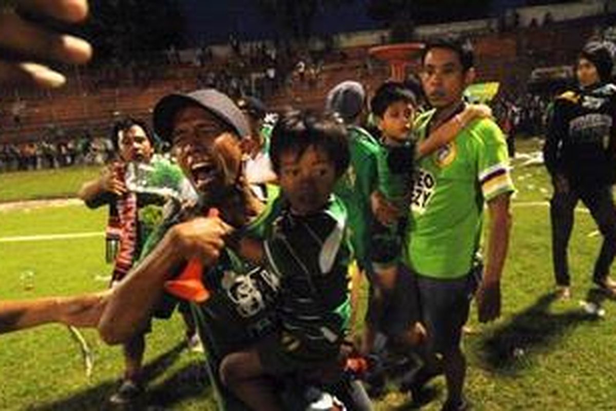 Pendukung Persebaya bersama anaknya menghindari paparan gas air mata yang dilepaskan aparat kepolisian seusai laga Liga Primer Indonesia antara Persebaya melawan Persija di Stadion Gelora 10 Nopember Surabaya, Minggu (3/6/2012). Aparat kepolisian terlibat bentrok dengan bonek seusai laga pertandingan yang berakhir imbang 3-3. 