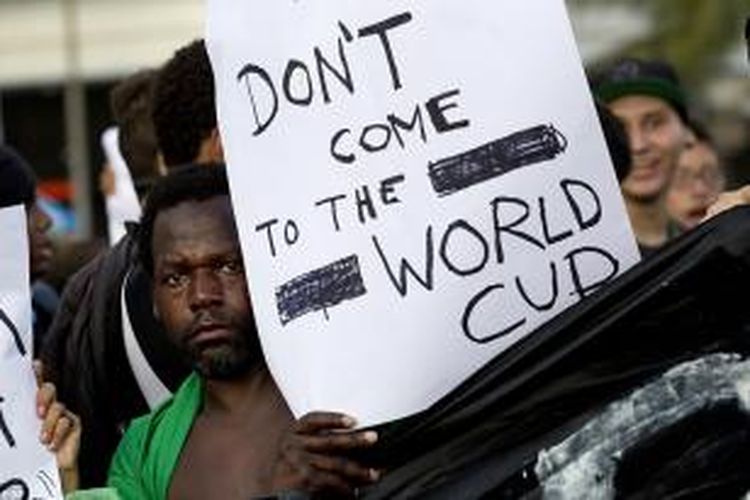 Seorang warga memegang poster berisi pesan agar turis dan penyuka sepak bola tidak datang ke Brasil saat penyelenggaraan Piala Dunia tahun ini