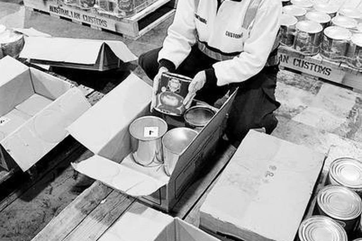 Petugas Bea Cukai Australia membuka kaleng berisi MDMA-ekstasi pada gambar yang dirilis hari Jumat (8/8). Tanggal persis penyitaan impor 4,4 ton pil ekstasi asal Italia menuju Melbourne ini masih tetap dirahasiakan.  