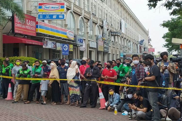 Warga berkerumun berdiri di belakang garis polisi di lokasi penyerangan kelompok John Kei di Green Lake City Kota Tangerang, Rabu (24/6/2020)