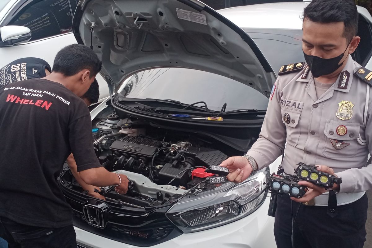 Satlantas Polresta Malang Kota melepas alat lampu strobo dan sirine dari mobil Honda Brio berwarna putih dengan nomor polisi B 2509 FIZ di Mapolresta Malang Kota pada Selasa (17/5/2022) siang. 