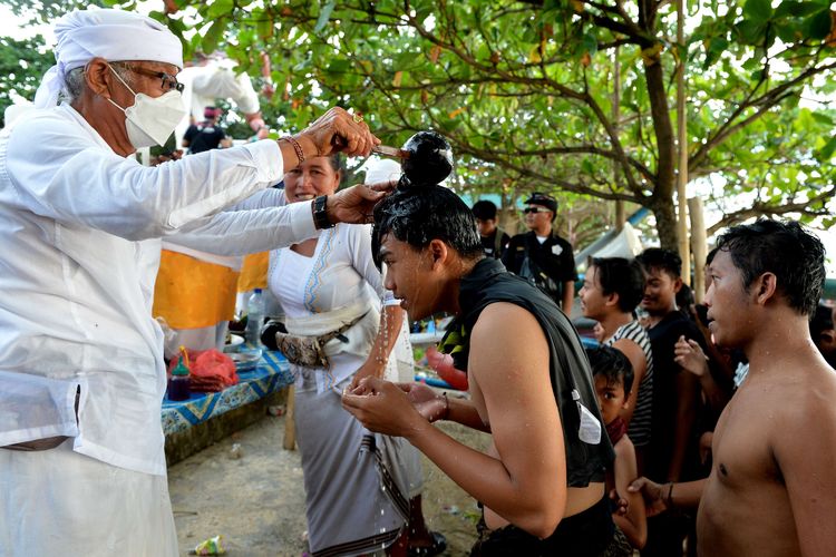 Pemuka agama Hindu memercikkan air suci kepada warga usai mengikuti tradisi Mebuug-Buugan atau mandi lumpur di Desa Kedonganan, Badung, Bali, Kamis (23/3/2023). Tradisi Mebuug-Buugan yang dilakukan setelah Hari Raya Nyepi tersebut dilakukan sebagai simbol menghilangkan kekotoran atau hal-hal negatif.