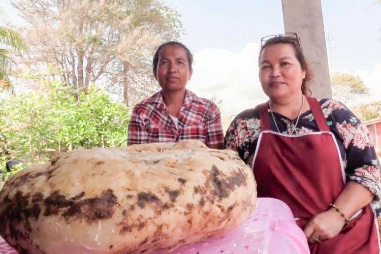 Siriporn Niamrin (kanan) berfoto dengan muntahan paus atau ambergris yang ditemukannya di pantai Nakhon Si Thammarat, Thailand selatan, pada 23 Februari 2021. Bongkahan itu harganya ditaksir sekitar Rp 3,7 miliar.