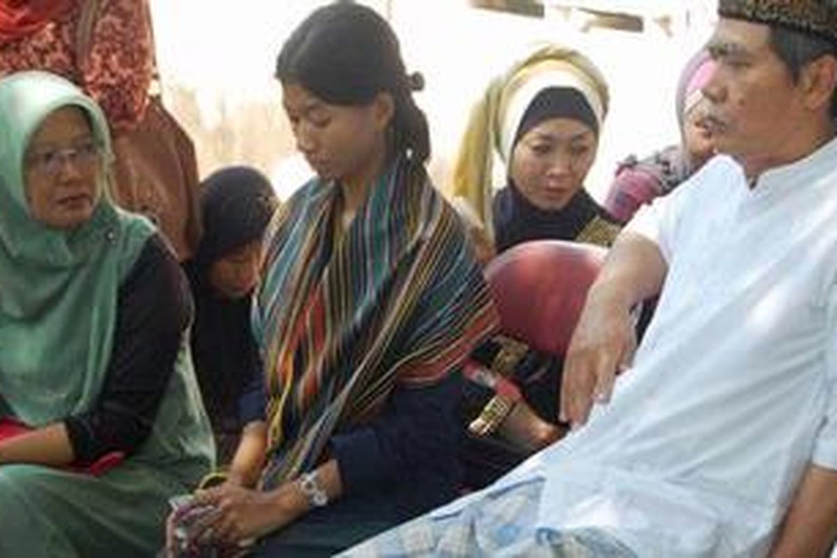 Istri almarhum Aditya (kedua dari kiri) dan ayah Aditya usai pemakaman Aditya di TPU Gading Kasri, Kota Malang. Kamis (24/5/2012).