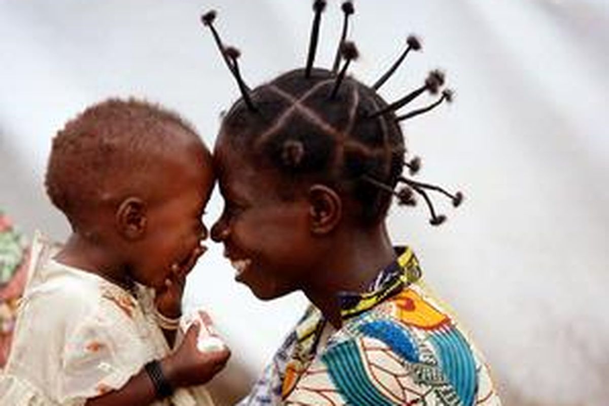 Seorang perempuan anggota milisi Kongo bercanda dengan anak perempuannya.