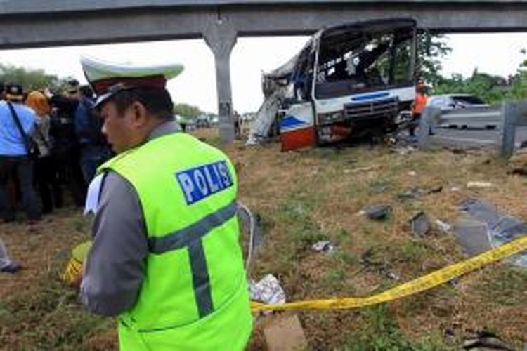 Petugas memasang garis polisi di lokasi kecelakaan bus Rukun Sayur dengan nomor polisi AD 1523 CF di kilometer 202 Tol Palimanan - Kanci, Cirebon, Jawa Barat, Selasa (14/7/2015). Sebanyak 11 orang meninggal dalam kecelakaan ini.