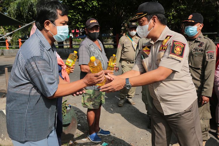 Petugas Satpol PP dan Satlinmas Kota Surabaya, Jawa Timur, membagikan 2.550 liter minyak goreng gratis kepada warga di Surabaya, Jumat (4/3/2022).