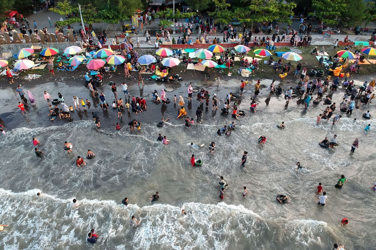 Foto udara wisatawan bermain air di Pantai Alam Indah (PAI) Tegal, Jawa Tengah, Selasa (3/5/2022). Pantai yang terletak di pinggir jalur Pantura itu menjadi salah satu tujuan wisata dari dalam maupun luar Kota Tegal saat libur lebaran.