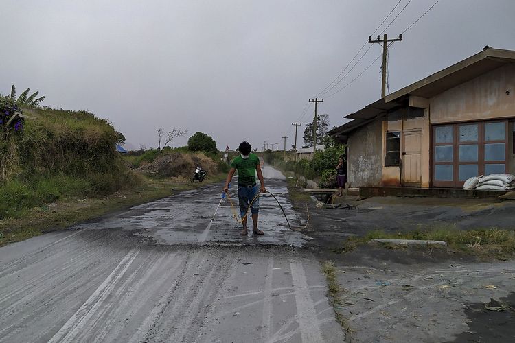 Warga membersihkan jalan yang dipenuhi debu vulkanik pasca erupsi Gunung Sinabung di Desa Sigarang-garang, Karo, Sumatera Utara, Sabtu (8/8/2020). Gunung Sinabung erupsi dengan tinggi kolom 2.000 meter. ANTARA FOTO/Sastrawan Ginting/Lmo/hp.
