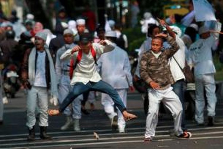 Massa Front Pembela Islam (FPI) melemparkan batu ke arah Gedung DPRD DKI Jakarta saat melakukan aksi unjuk rasa, Jumat (3/10/2014). Massa FPI berdemo menolak Ahok diangkat menjadi Gubernur DKI Jakarta.