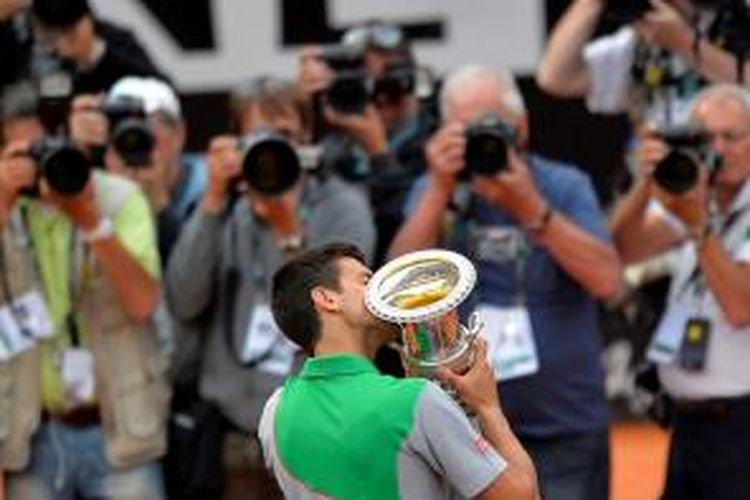 Petenis Serbia Novak Djokovic mencium trofi Roma Masters di depan para fotografer yang mengabadikannya. Djokovic juara di Roma Masters setelah mengalahkan petenis Spanyol, Rafael Nadal, 4-6, 6-3, 6-3, Minggu (18/5/2014).