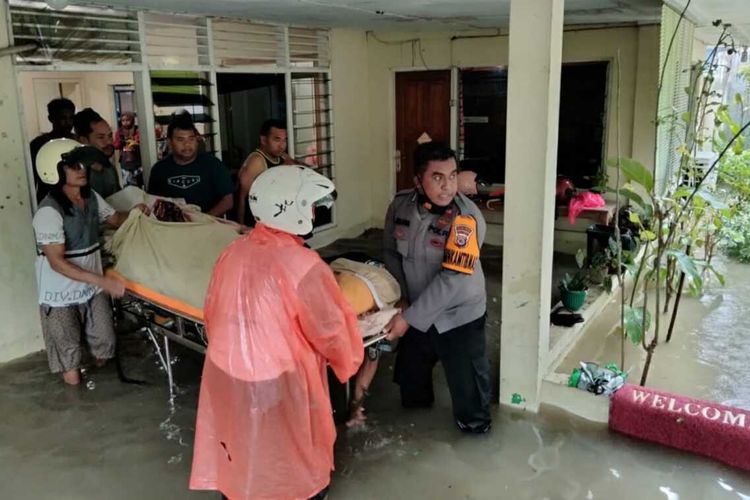 Seorang anggota Babinkantibmas bersama warga berusaha mengevakuasi seorang lansia yangs edang sakit dari sebuah rumah yang terendam banjir di Kelurahan Namaelo Kota Masohi, Kabupaten Maluku Tengah, Minggu (17/7/2022)