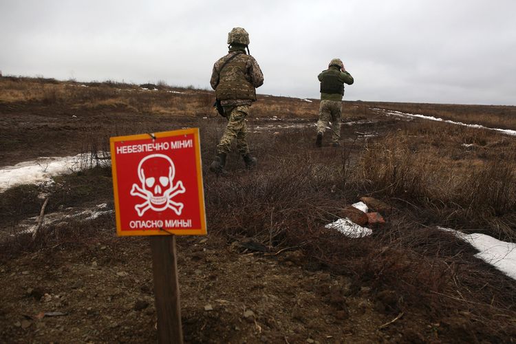 Tentara Ukraina berjalan melewati tanda peringatan awas ranjau di garis depan perlawanan menghadapi separatis pro-Rusia dekat desa Luhansk, wilayah Donetsk, 11 Januari 2022.