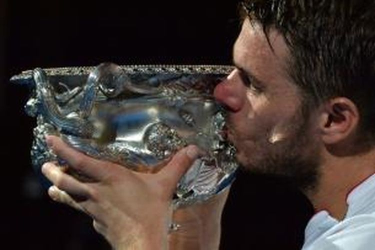 Petenis Swiss, Stanislas Wawrinka mencium trofi juara Australian Open setelah memenangi laga final melawan petenis Spanyol, Rafael Nadal di Rod Laver Arena, Melbourne Park, Minggu (26/01/2014). Wawrinka menang 6-3, 6-2, 3-6, 6-3.