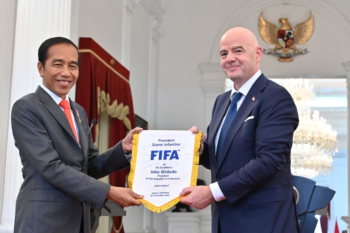 Gianni Infantino (R), president of football's world governing body FIFA, presents a souvenir to Indonesia's President Joko Widodo (L) during a joint press statement at the Presidential Palace in Jakarta on October 18, 2022. Infantino on October 18 vowed to help the Indonesian government to help reform and transform the country's football in the aftermath of a stadium disaster that claimed over 130 lives and injured hundreds.