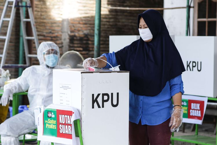 Warga menggunakan hak pilihnya di Tempat Pemungutan Suara (TPS) 39 Banjarsari, dalam pemilihan Walikota dan Wakil Walikota Solo, Rabu (9/12/2020). Mengangkat tema TPS sadar protokol kesehatan, petugas TPS 39 terlihat mengenakan hasmat serta warga yang datang diwajibkan menggunakan masker, mencuci tangan, dan mengenakan sarung tangan.