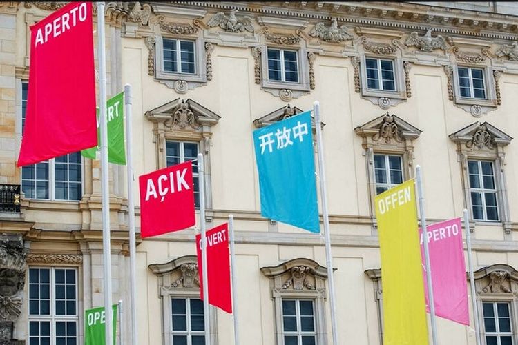 Bendera dengan tulisan 'Buka' dalam berbagai bahasa terlihat di depan Forum Humboldt sejak 20 Juli 2021. Pekan depan museum ini akan dibuka secara resmi dibuka untuk umum. 