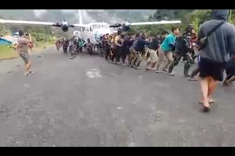 Tangkapan layar yang menunjukan puluhan masyarakat ikut membantu aparat TNI-Polri menarik pesawat yang sebelumnya tergelincir di Bandara Beoga, Kabupaten Puncak, Papua Tengah, Senin (23/1/2023)