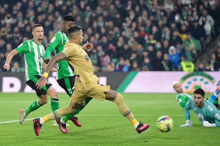 Raphinha saat mencetak gol dalam pertandingan Real Betis vs Barcelona pada laga tunda ke-17 Liga Spanyol 2022-2023 di Stadion Benito Villamarin, Kamis (2/2/2023). Duel Real Betis vs Barcelona tuntas dengan skor 1-2. (Foto oleh CRISTINA QUICLER / AFP)