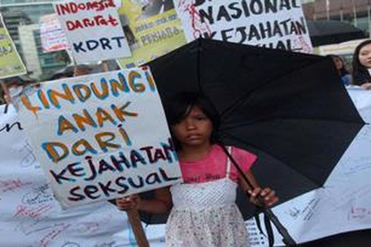 Seorang anak bersama warga lainnya  membawa poster saat mengikuti aksi unjukrasa menolak kejahatan seksual yang digelar oleh Koalisi Aksi Solidaritas Darurat Nasional Kejahatan seksual Terhadap Anak di Bundaran Hotel Indonesia, Jakarta Pusat, Minggu (13/1/2013). Selain meminta pemerintah untuk membangun sistem perlindungan anak dan perempuan, aksi itu juga meminta peningkatan hukuman penjara minimal 20 tahun bagi pelaku. 