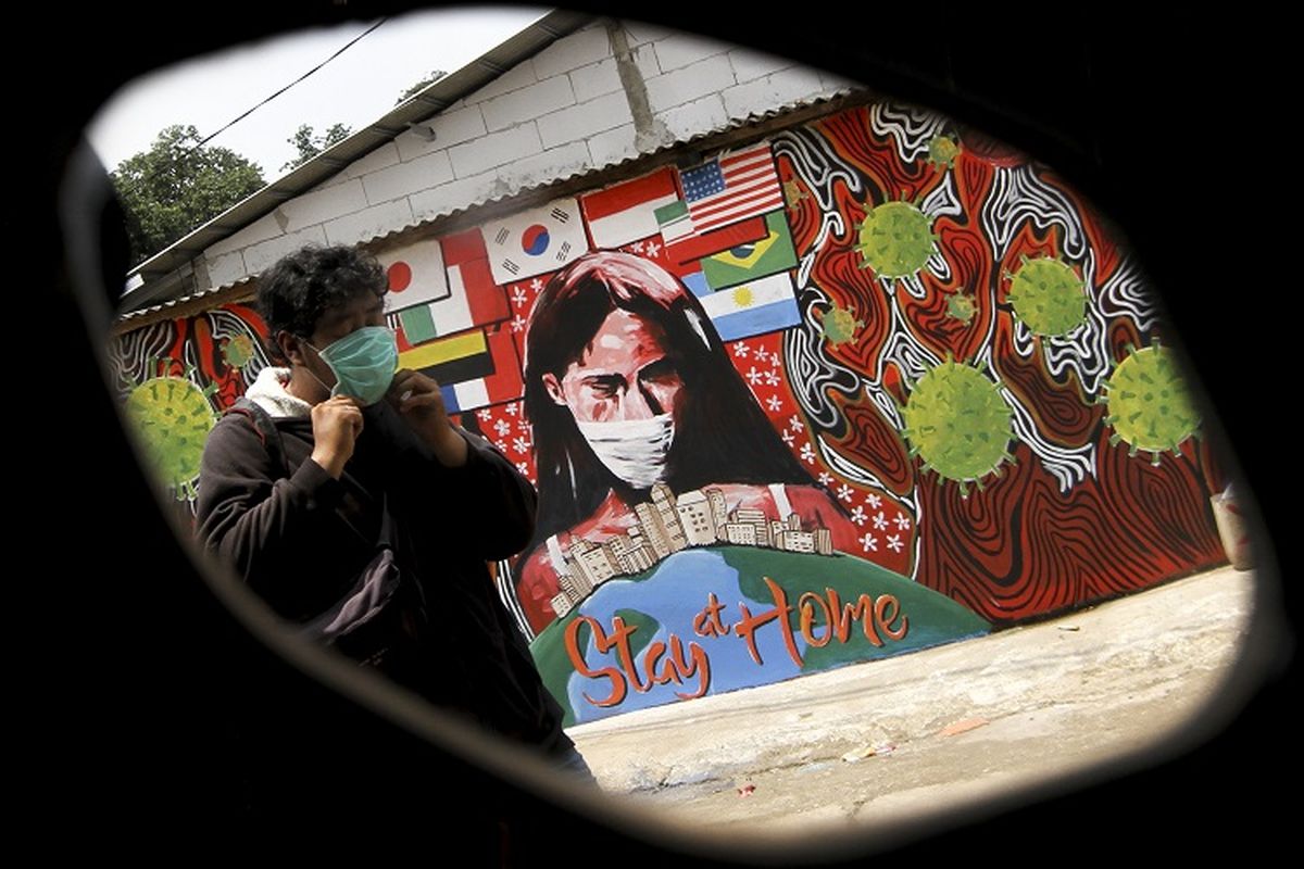 Seorang Warga melintas di depan mural bertuliskan Stay At Home di Cipayung, Depok, Jawa Barat, Selasa (14/4/2020). Pemerintah Kota Depok akan menerapkan Pembatasan Sosial Berskala Besar (PSBB) mulai Rabu (15/4) sebagai upaya memutus rantai penyebaran virus corona COVID-19. ANTARA FOTO/Asprilla Dwi Adha/hp.