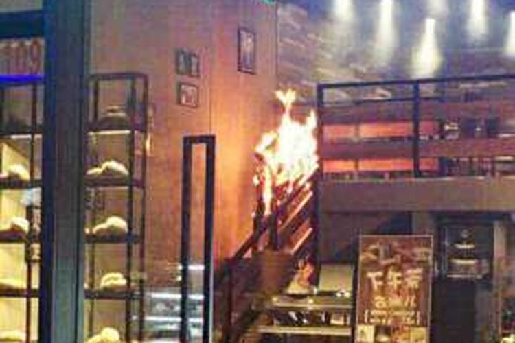 Dalam foto yang diambil seorang pengunjung kafe di Shanghai, China terlihat penyanyi pop China Tang Anqui (24) berlari dari lantai dua kafe itu dengan tubuh yang sudah dilalap api.