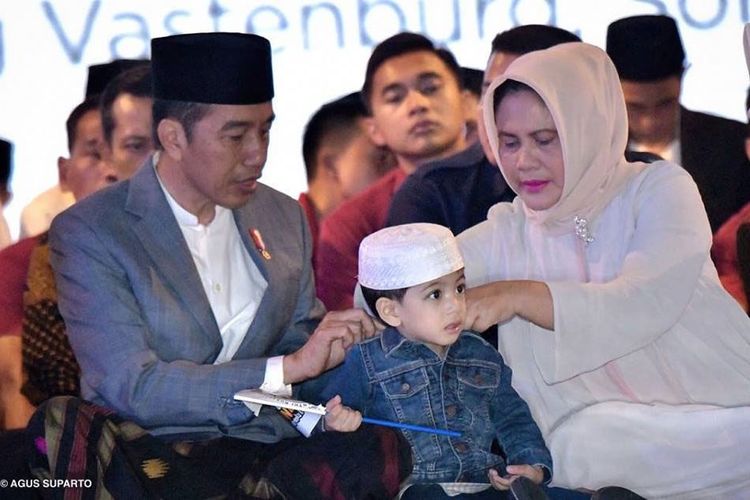 Presiden Jokowi sedang memakaikan jaket jins kepada cucunya, Jan Ethes saat merayakan Hari Santri Nasional di Solo, Minggu (21/10/2018).