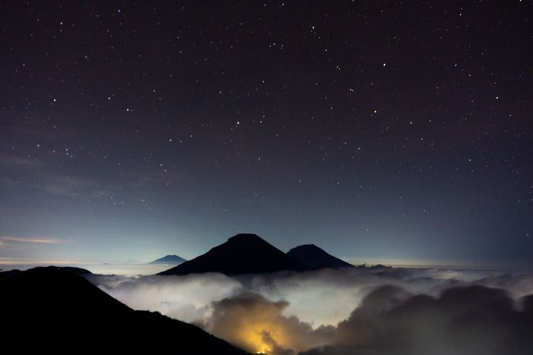 Panorama malam di Gunung Bismo, Wonosobo. Terlihat Gunung Sumbing, Sindoro, dan Merbabu yang seolah terbang di atas awan.