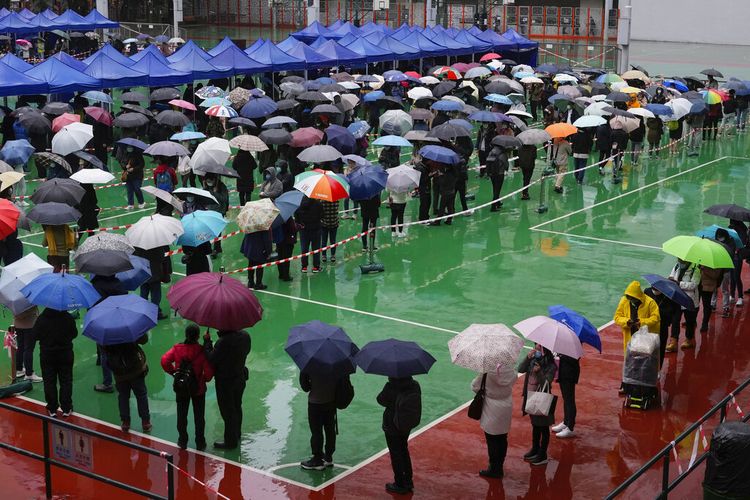 Warga mengantre untuk dites virus corona di pusat pengujian sementara meskipun hujan di Hong Kong, Senin, 21 Februari 2022.