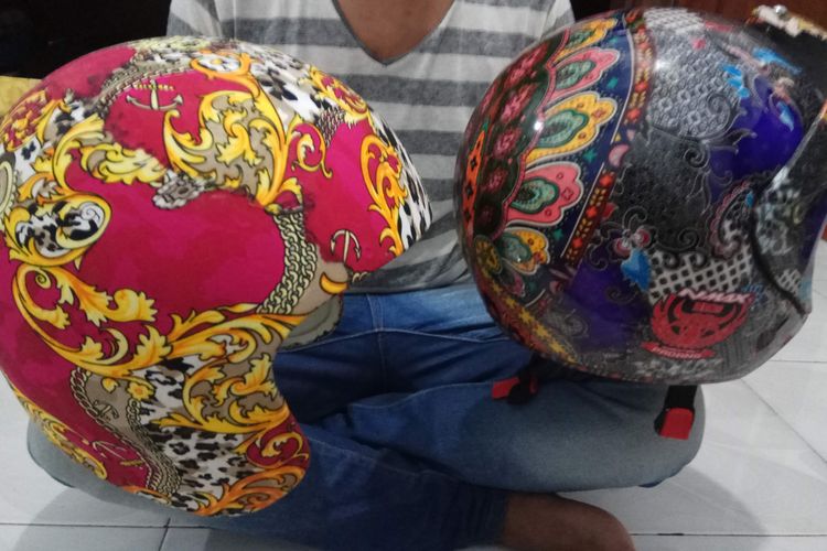 Hendry, keponakan dari Fajri Uda Black modifikator Yamaha NMax batik, menunjukkan helm batik yang tengah dikerjakannya.