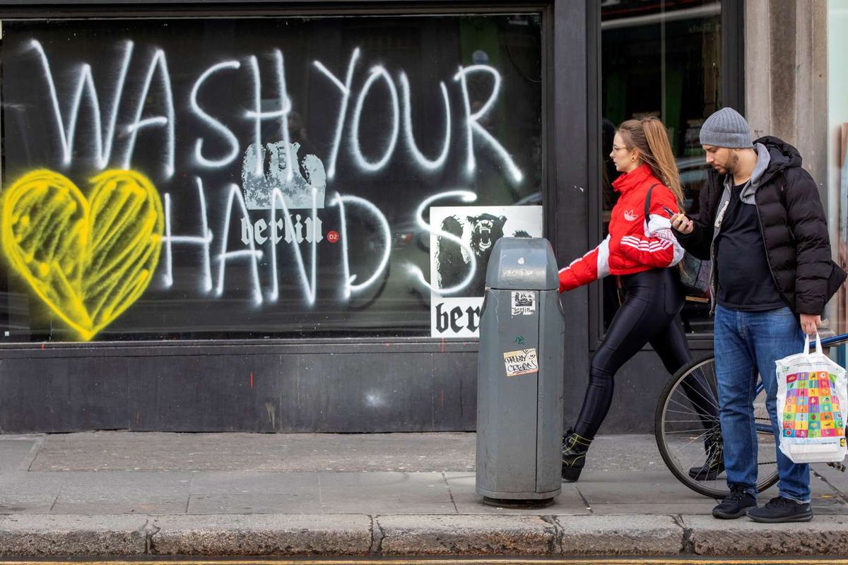 Pejalan kaki melintas di depan grafiti yang berisikan pesan untuk mencuci tangan di Dublin, Irlandia, 13 Maret 2020. Pandemi Covid-19 yang disebabkan oleh virus corona menjadi insipirasi seniman grafiti untuk memberikan peringatan dan motivasi bagi warga dalam menghadapi virus tersebut.