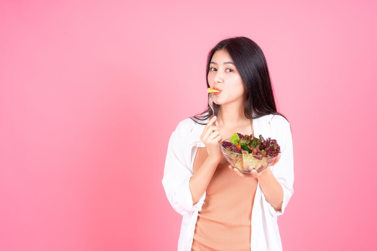 Ilustrasi wanita sedang memakan sayuran.