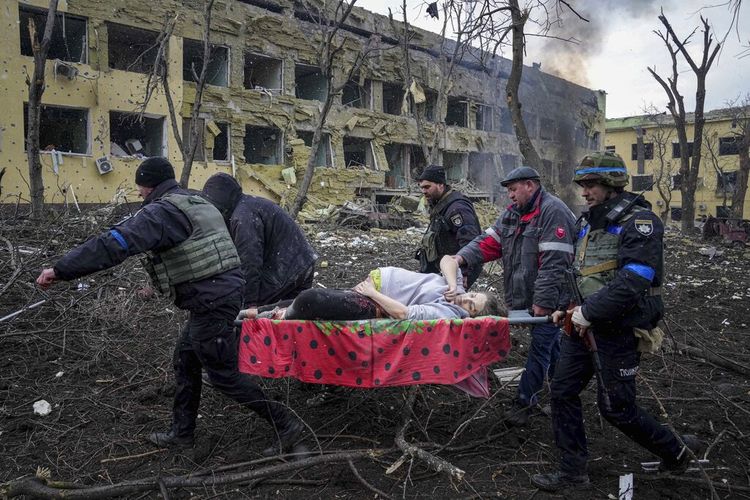 Pekerja darurat Ukraina dan sukarelawan membawa seorang wanita hamil yang terluka dari rumah sakit bersalin yang rusak akibat penembakan di Mariupol, Ukraina, Rabu, 9 Maret 2022.