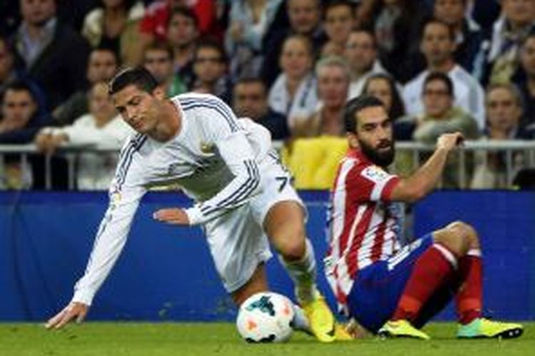 Gelandang Real Madrid Cristiano Ronaldo (kiri) berebut bola dengan gelandang Atletico Madrid Arda Turan, pada laga Liga BBVA, di Santiago Bernabau, Sabtu (28/9/2013). Laga itu berakhir 1-0 untuk Atletico.