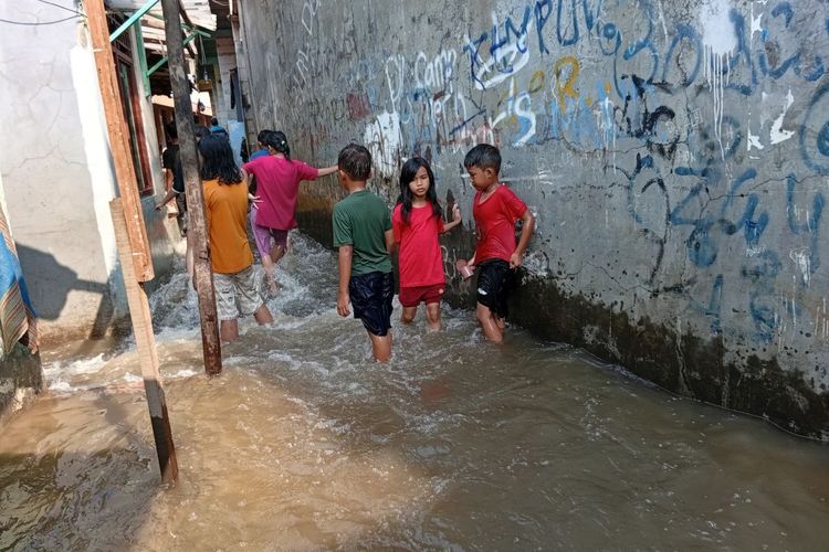 Banjir di Jati Padang dijadikan wahana bermain air oleh anak-anak sembari petugas SDA berusaha menutupi area tangggul yang jebol, Jumat (31/10/2025).