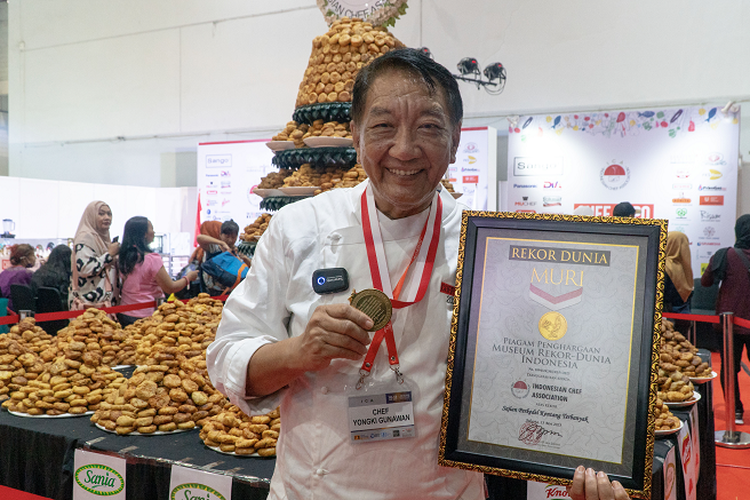 Chef Yongki Gunawan memegang Piagam Penghargaan MURI dengan latar belakang tumpeng yang terbuat dari 16.000 buah perkedel. 