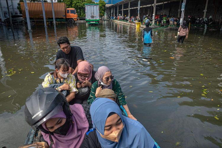 Sejumlah karyawan menyewa perahu bermotor untuk menerobos banjir limpasan air laut ke daratan atau rob di kawasan industri Pelabuhan Tanjung Emas Semarang, Jawa Tengah, Jumat (27/5/2022). Karyawan sejumlah pabrik setempat mulai membersihkan sisa-sisa banjir rob di dalam pabrik yang berangsur surut, meskipun air rob masih merendam sejumlah titik akses keluar - masuk kawasan industri pelabuhan dengan ketinggian bervariasi hingga sekitar 70 sentimeter.