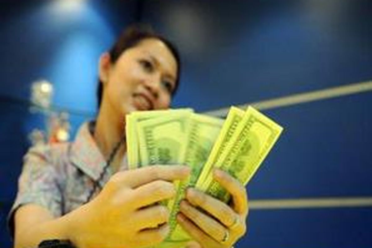 Petugas menghitung dolar AS di pasar valuta asing (Valas) Bank Mandiri, Jakarta, Jumat (10/10). 