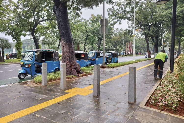 Abdul (44) sedang membersihkan sampah di kawasan depan Perpusnas, Jakarta Pusat, pada Minggu (26/2/2023).