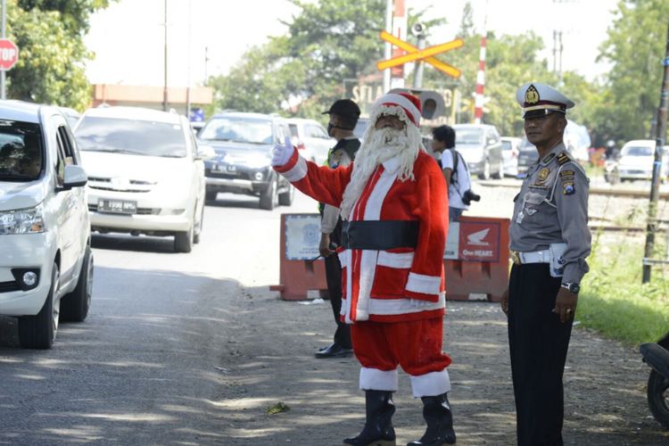 Sinterklas yang diperankan seorang relawan membantu aparat Satlantas Polres Madiun mengatur arus lalu lintas di salah titik kemacetan di ruas jalan Surabaya-Madiun,  Kabupaten Madiun, Jawa Timur, Senin ( 25/12/2017).