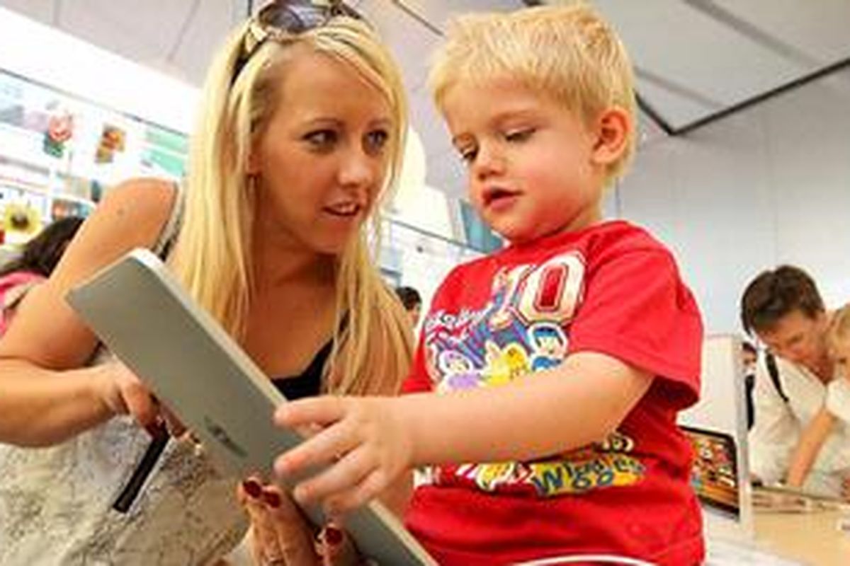 Seorang ibu sedang berinteraksi dengan anak lelakinya ketika menggunakan iPad