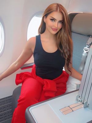 Gaya kasual Miss Universe Arab Saudi 2024, Rumy Alqahtani, saat akan pergi ke Dubai, dengan mengenakan tanktop hitam dan celana merah. 