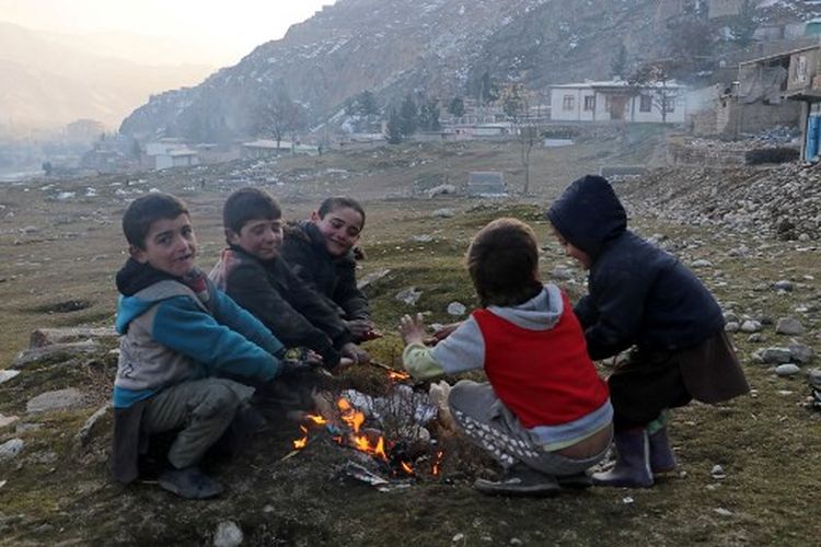 Anak-anak Afghanistan menghangatkan diri di sekitar kebakaran di distrik Fayzabad provinsi Badakhshan pada 26 Januari 2023. Afghanistan tengah diterjang cuaca dingin ekstrem.