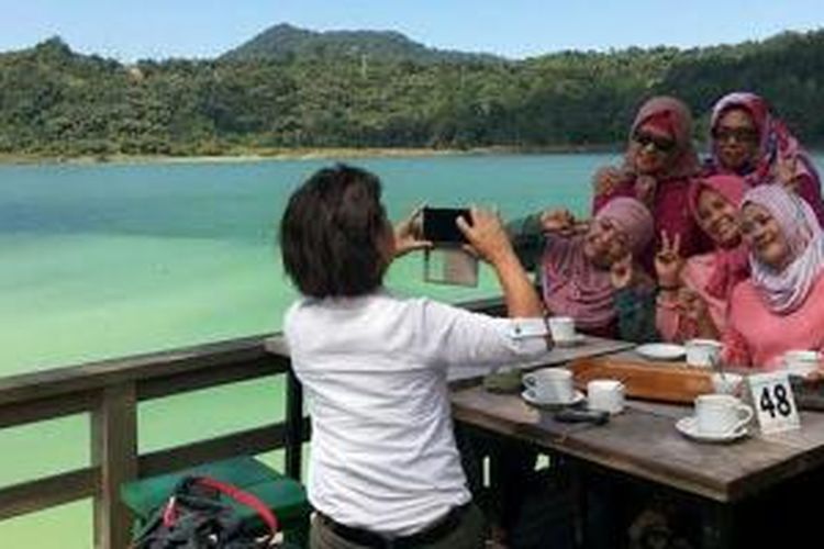 Sejumlah wisatawan selfie dengan latar belakang pesona Danau Linow di Tomohon, Sulawesi Utara.