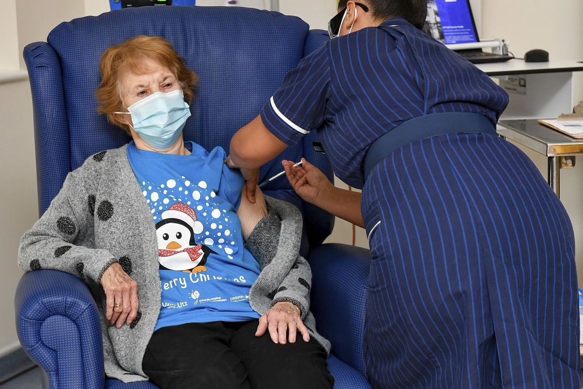Foto tertanggal 8 Desember 2020 menunjukkan Margaret Keenan (90) menjadi pasien pertama di Inggris yang disuntik vaksin Covid-19 buatan Pfizer-BioNTech. Penyuntikan dilakukan oleh perawat May Parsons di University Hospital. Coventry, Inggris.