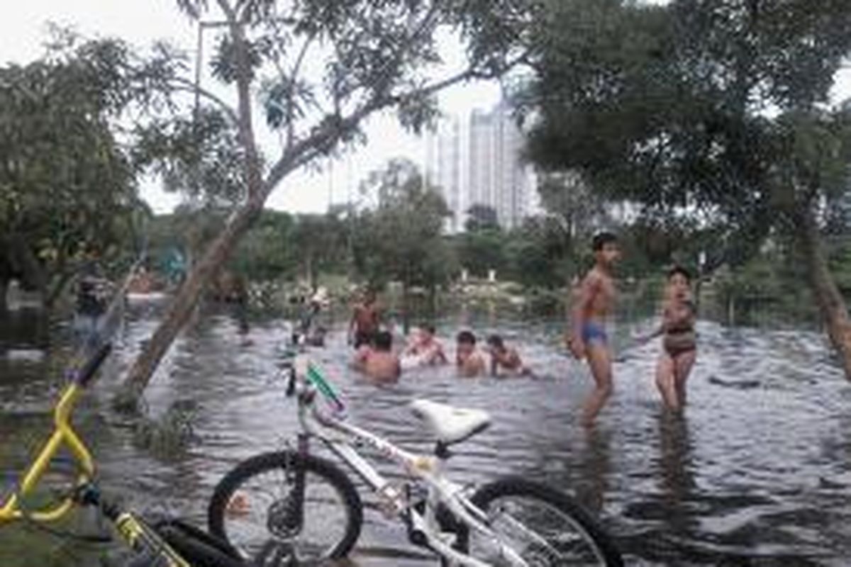 Anak-anak bermain di genangan banjir TPU Karet Bivak.