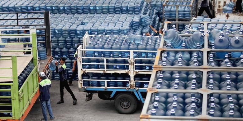 Karyawan perusahaan air minum dalam kemasan sedang bersiap mendistribusikan ratusan galon air ke dalam truk pengangkut.