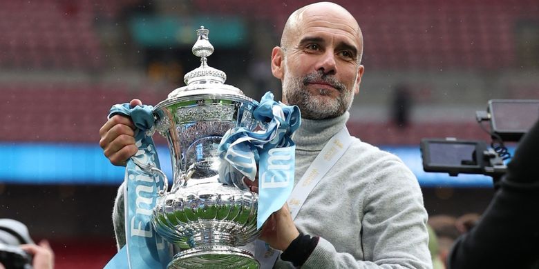 Pep Guardiola berpose dengan trofi setelah pertandingan sepak bola final Piala FA antara Chelsea vs Manchester City di stadion Wembley di London, pada 16 Mei 2026. Manchester City memenangkan pertandingan dengan skor 1-0. (Foto oleh Adrian Dennis / AFP)