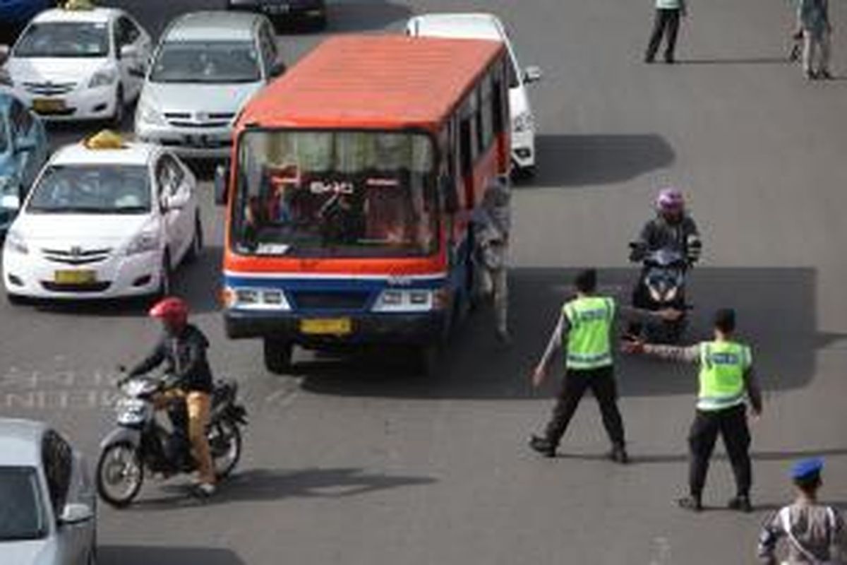 Gabungan petugas kepolisian dan Dinas Perhubungan DKI mengarahkan pengendara sepeda motor yang akan melintas di Jalan MH Thamrin, Jakarta Pusat, Rabu (17/12/2014). Di hari pertama uji coba pembatasan sepeda motor sepanjang Jalan Thamrin-Medan Merdeka Barat, masih terdapat sejumlah pengendara yang belum mengetahui aturan tersebut. KOMPAS/LUCKY PRANSISKA 